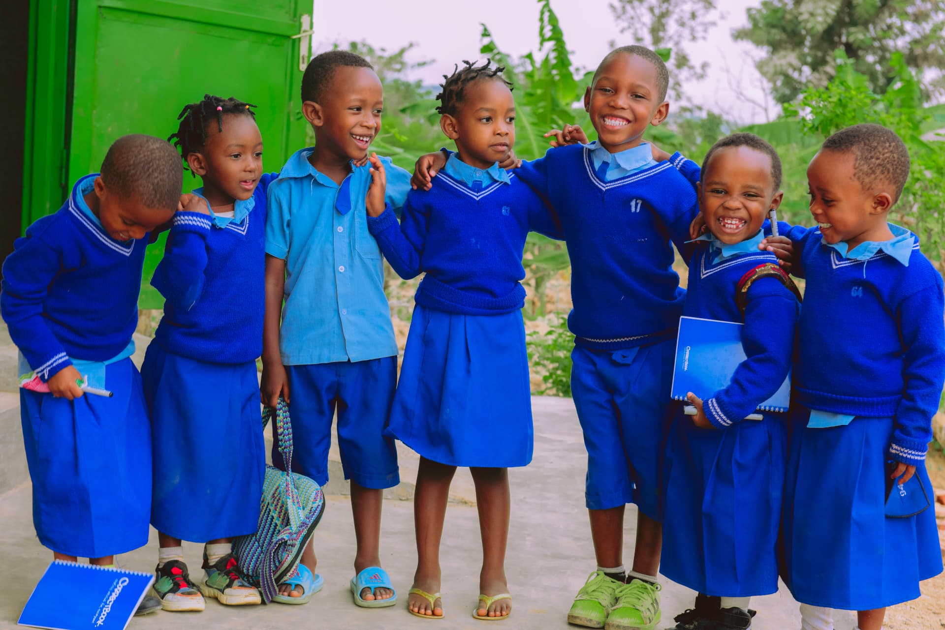 Children in blue school uniforms smiling and holding Correctbook notebooks